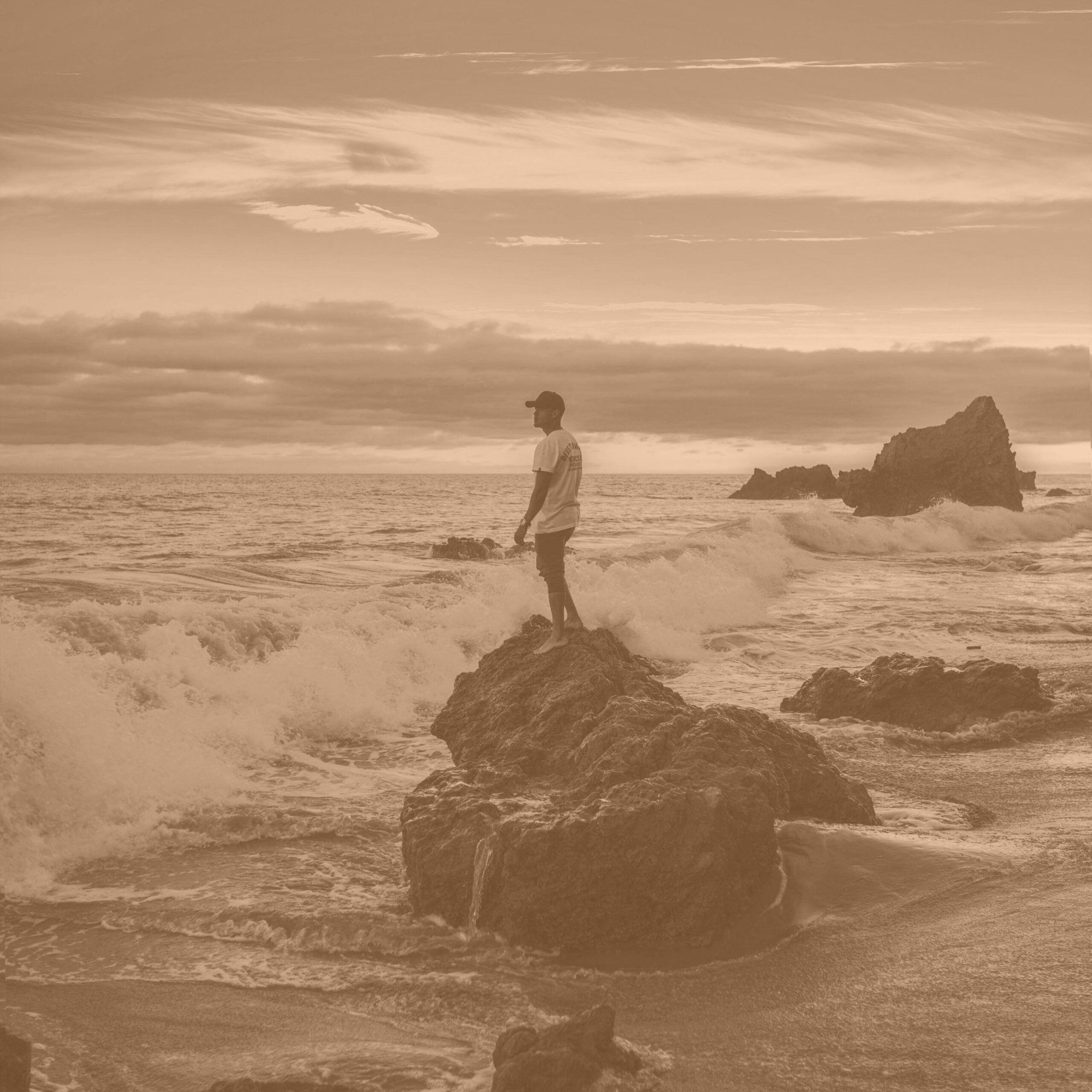 Man standing on a rock at the edge of the ocean