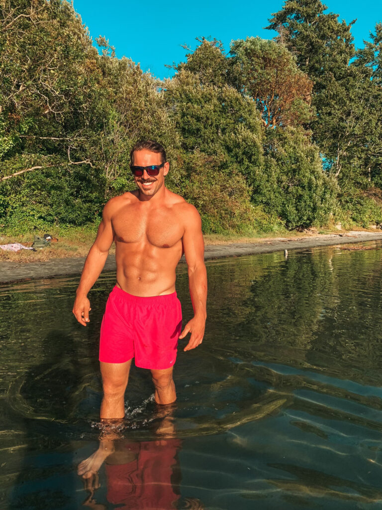 Brandon in pink shorts standing in the water in the summertime